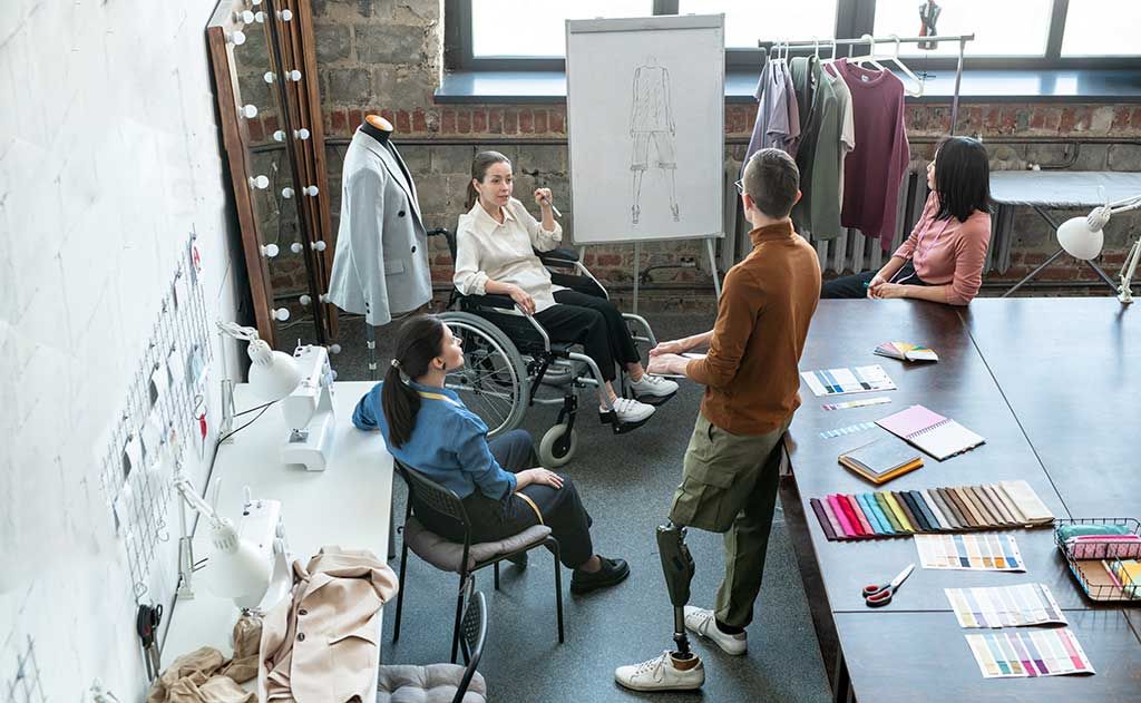 Diverse team of all abilities review sketches and swatches for inclusive garments in design and product development stages.
