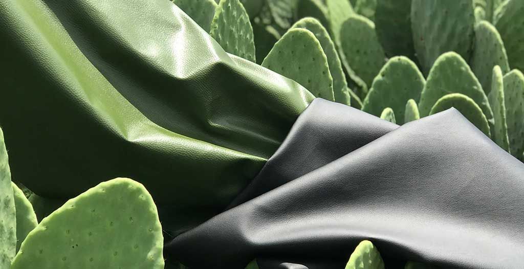 Green and black sheets of cactus leather laid over cactus paddles. 